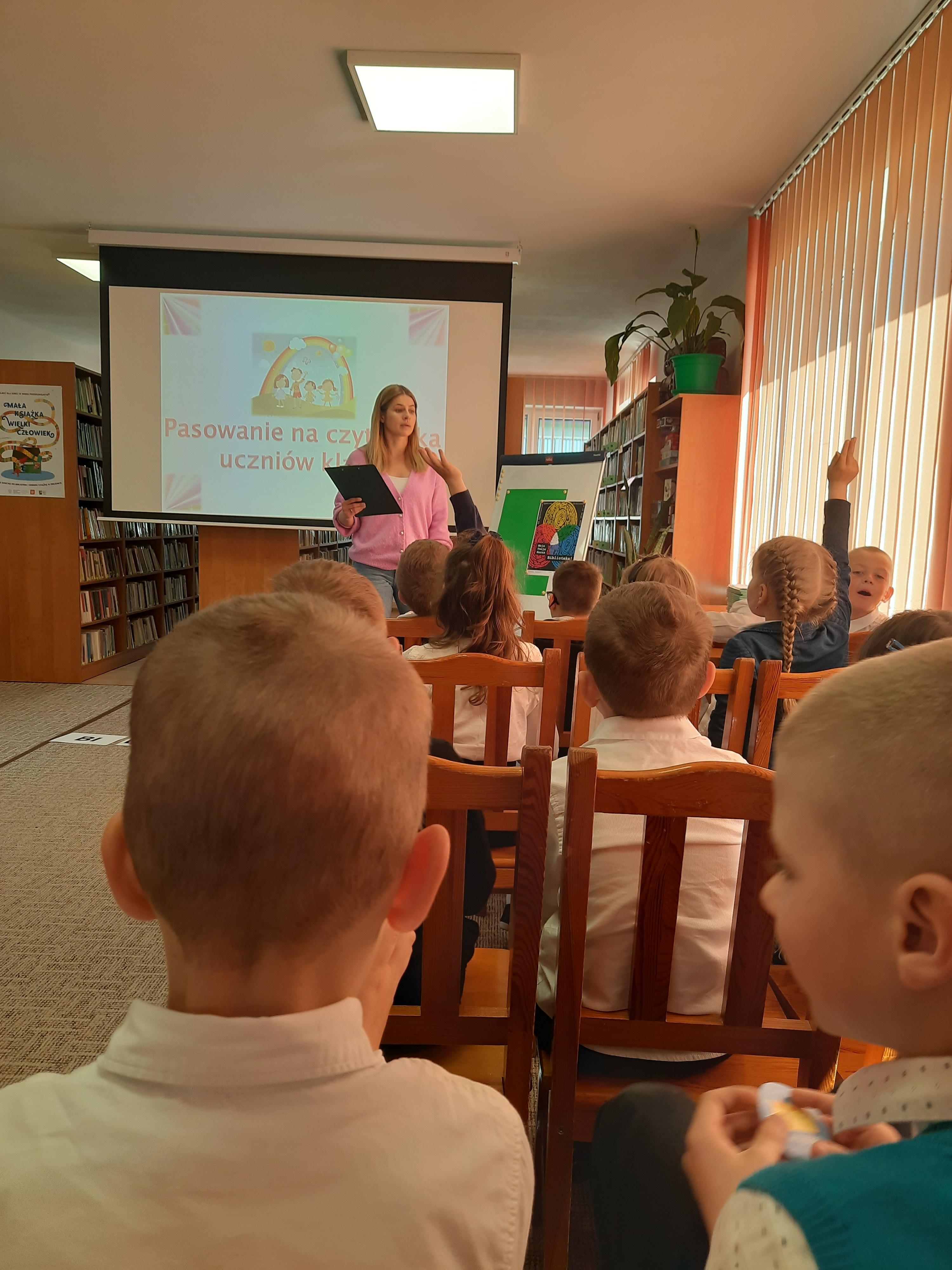 Bibliotekarka_Michalina_Kurpiewska_wita_uczni&oacute;w_kl-_Ib_na_uroczystości_pasowania_na_czytelnika-