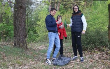 Uczniowie sprzątają butelki w pobliskim lesie