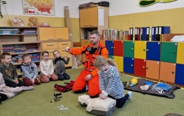Pola wykonuje masaż serca na fantomie, ratownik pokazuje dzieciom wposażenie stroju