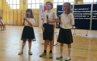 Marcelina Niedźwiecka z kl. I, Kajetan Niedźwiecki z kl. II b i Sara Ostrowska z kl. II b śpiewają piosenkę Sutanna