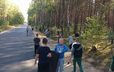 Piątoklasiści sprzątają pobocze drogi ze śmieci.