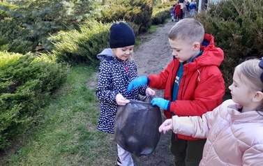 Uczniowie klasy Ib  sprzątają przyszkolny plac zabaw.