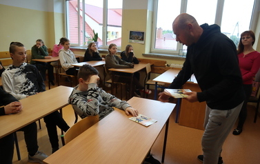 Jacek Żylak rozdaje uczniom ulotki z zalożeniami programu.