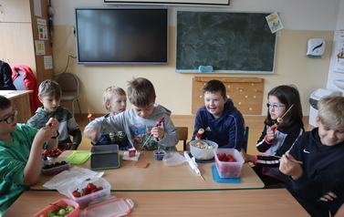Drugoklasiści wykonują szaszłyki z owoc&oacute;w.
