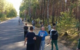 Piątoklasiści sprzątają pobocze drogi ze śmieci.